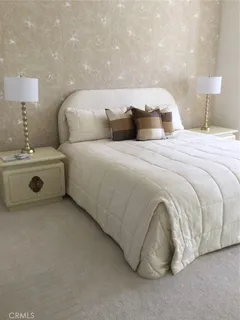 a bedroom with a bed and a lamp on dresser