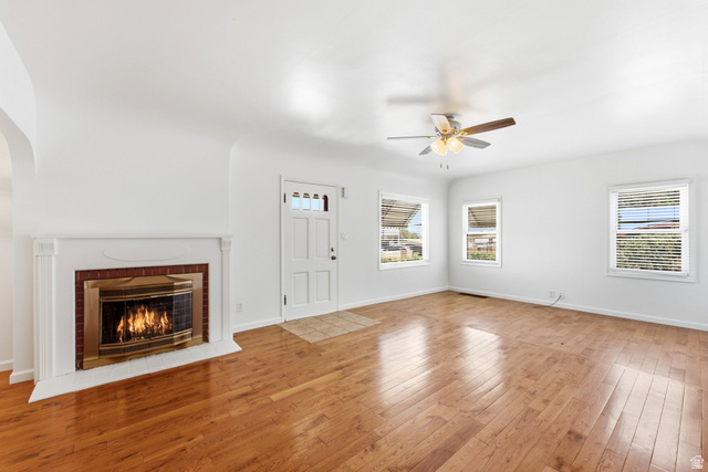 1925 South Main Street Bountiful, UT 84010 - Photo 11 of 48 Living space featuring wood-finish flooring, a white mantel fireplace with a brass-trimmed insert, and a ceiling fan with integrated lighting