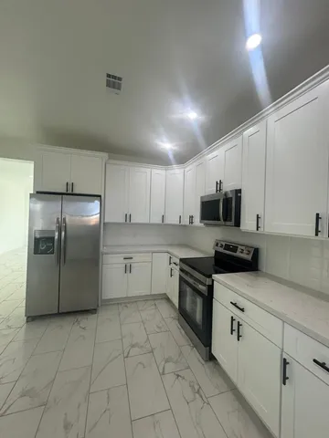 a kitchen with stainless steel appliances granite countertop a refrigerator sink and white cabinets