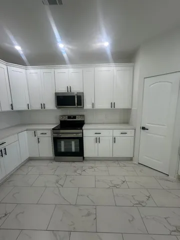 a kitchen with white cabinets a sink and white appliances