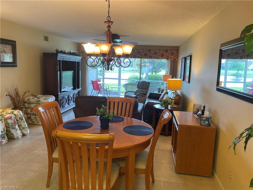 5970 Amherst Drive, Unit C103 Naples, FL 34112 - Photo 8 of 24 Dining room with light tile patterned floors and a chandelier