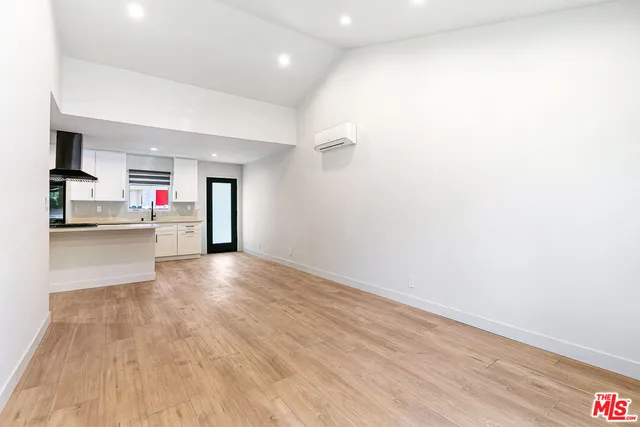 a view of a room with wooden floor and kitchen view