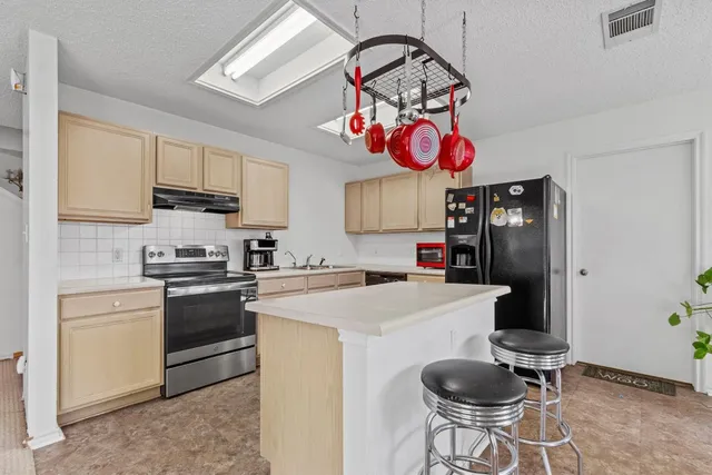 a kitchen with stainless steel appliances granite countertop a sink a stove and a refrigerator