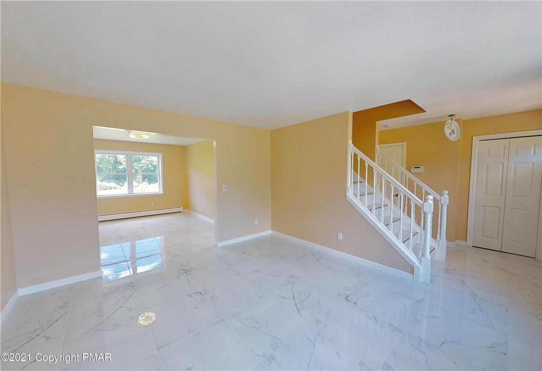 1110 Misty Ridge East Stroudsburg, PA 18302 - Photo 19 of 43 A graceful staircase ascends from a well-lit living area featuring pristine marble flooring.