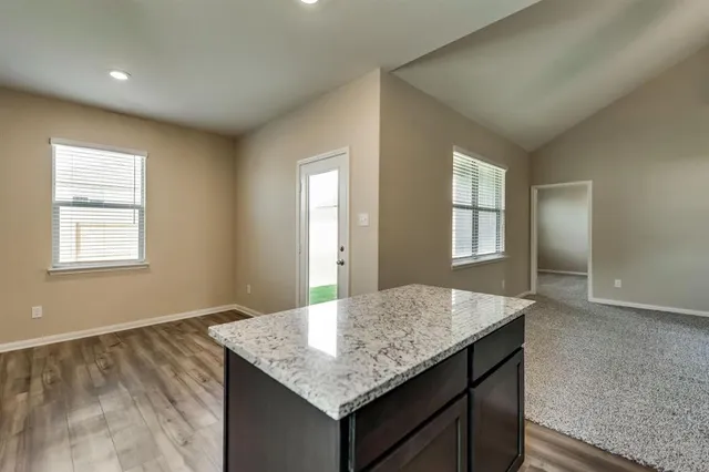 an empty room with a kitchen island wooden floor and window
