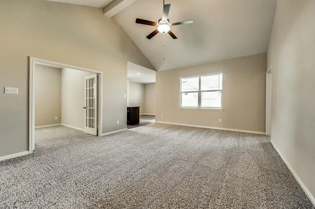 an empty room with chandelier fan and windows