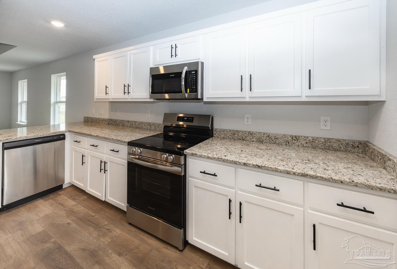 5303 Zenith Lane Milton, FL 32583 - Photo 8 of 16 a kitchen with granite countertop white cabinets and white appliances