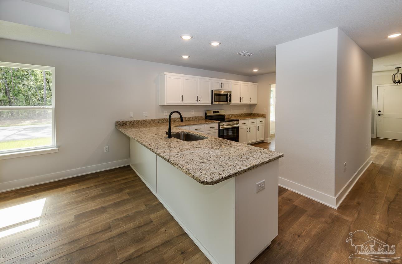 5303 Zenith Lane Milton, FL 32583 - Photo 9 of 16 a kitchen with a sink window and cabinets