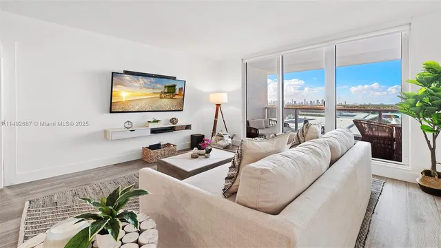 a living room with furniture a flat screen tv and a floor to ceiling window