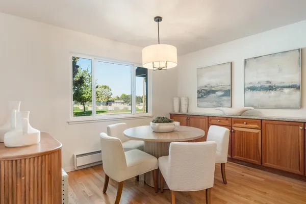 a dining room with wooden floor a chandelier a wooden table and chairs