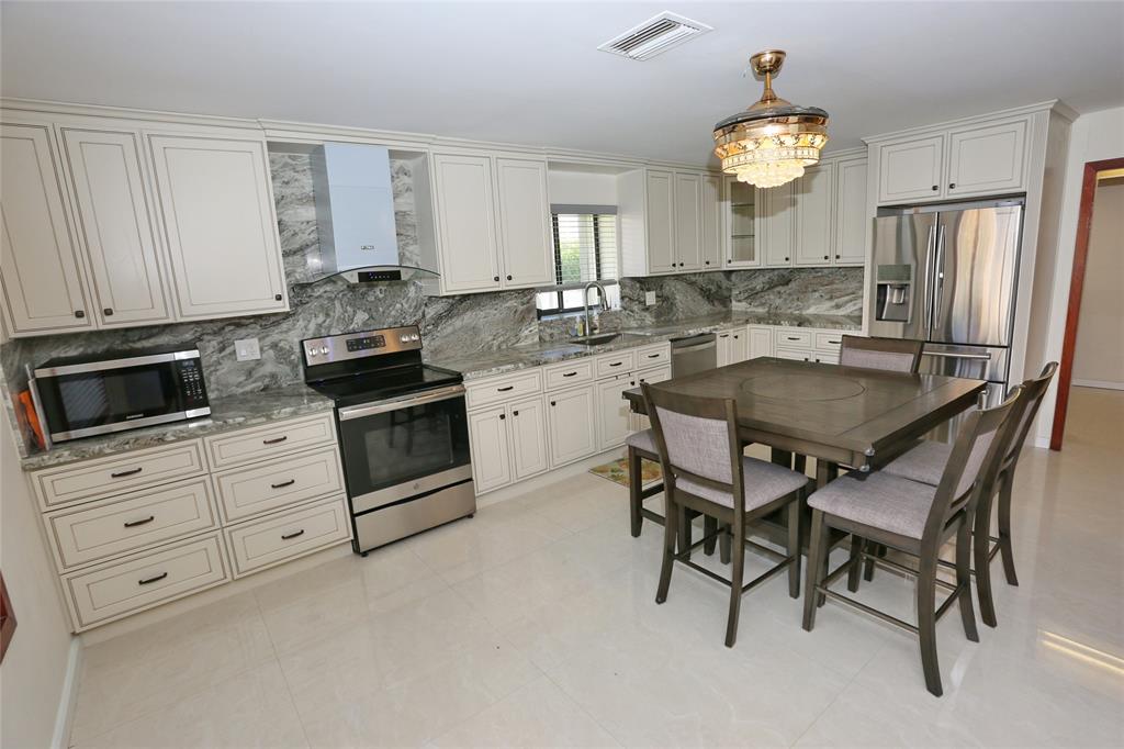 100 Circle Drive Pompano Beach, FL 33062 - Photo 7 of 30 a kitchen with granite countertop white cabinets and stainless steel appliances