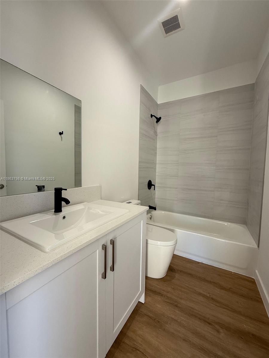 416 Southwest 1st Street, Unit 416 Florida City, FL 33034 - Photo 18 of 24 a bathroom with a granite countertop sink toilet a mirror and bathtub