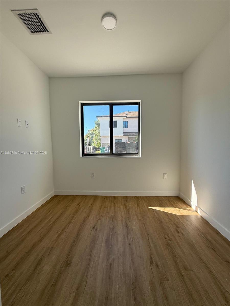 416 Southwest 1st Street, Unit 416 Florida City, FL 33034 - Photo 23 of 24 an empty room with wooden floor and windows