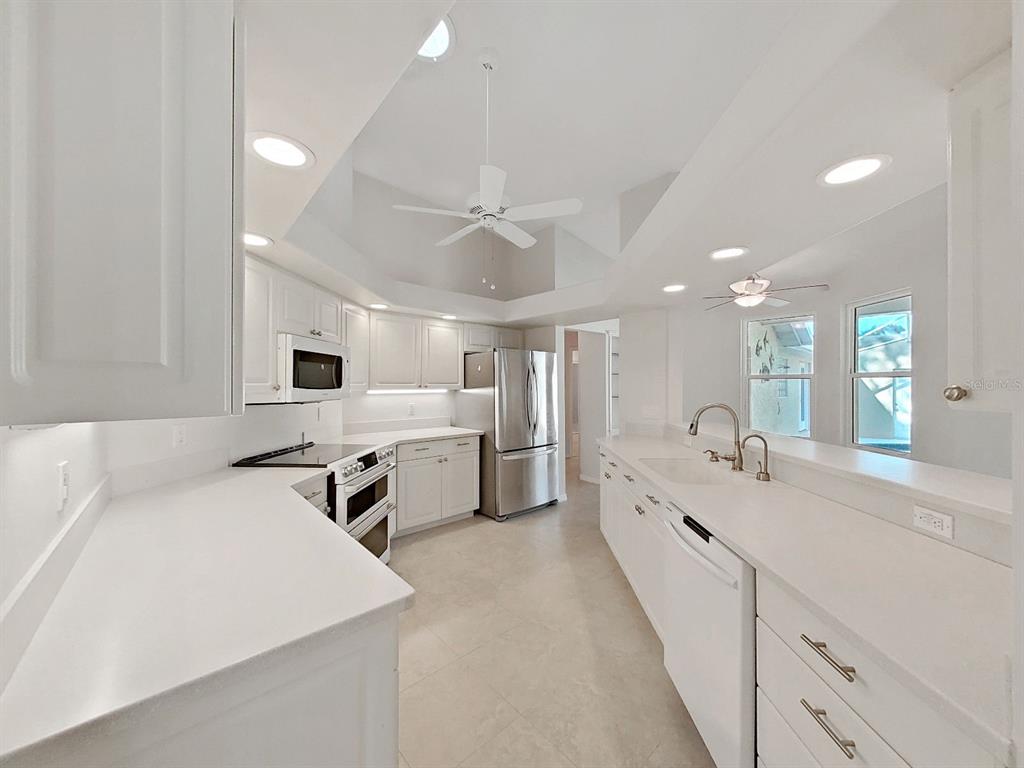 14595 Oliver Street Largo, FL 33774 - Photo 11 of 35 a large white kitchen with a large counter top appliances and cabinets