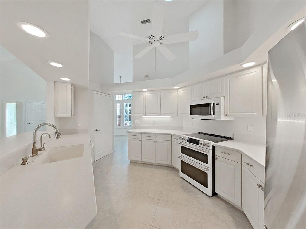 14595 Oliver Street Largo, FL 33774 - Photo 12 of 35 a kitchen with white cabinets and stainless steel appliances