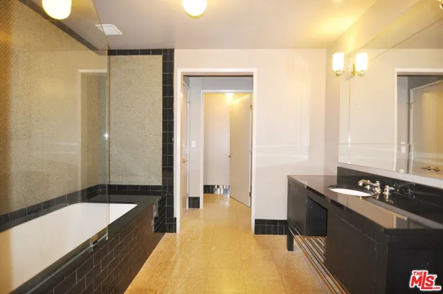 a spacious bathroom with a tub sink and mirror
