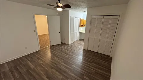 an empty room with wooden floor closet and windows