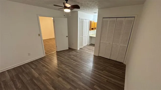 an empty room with wooden floor closet and windows