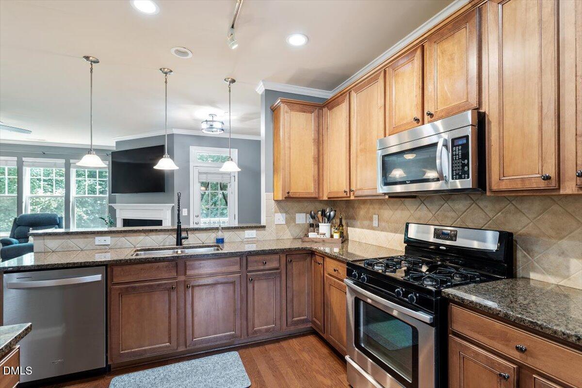 6224 Braidwood Court Raleigh, NC 27612 - Photo 16 of 39 a kitchen with stainless steel appliances granite countertop a stove a sink and a microwave