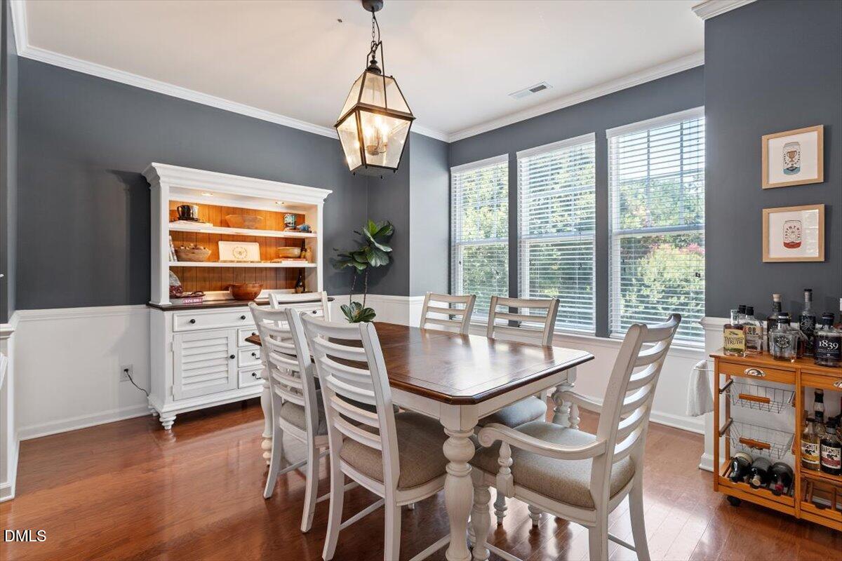 6224 Braidwood Court Raleigh, NC 27612 - Photo 5 of 39 a dining room with wooden floor a chandelier a glass table and chairs