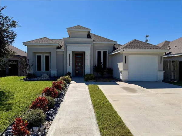 a front view of a house with a yard and potted plants