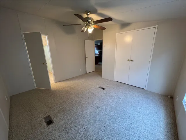 a view of an empty room with a ceiling fan and window