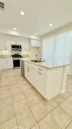 a kitchen with a sink a stove top oven and white cabinets