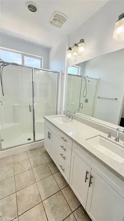 a bathroom with a double vanity sink mirror and shower