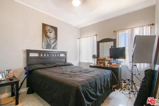 a bedroom with a bed a flat screen tv and a chandelier