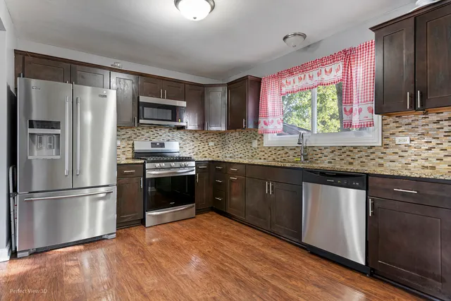 a kitchen with stainless steel appliances granite countertop a refrigerator a sink dishwasher a stove with wooden cabinets and floor