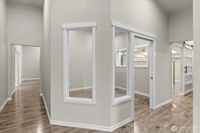 a view of a hallway with wooden floor and a bathroom