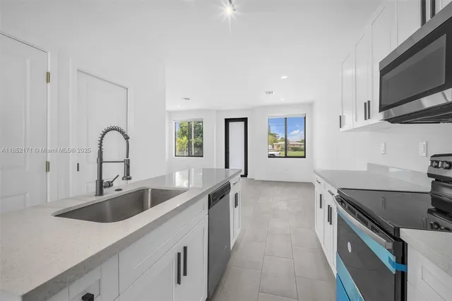 a kitchen with kitchen island granite countertop a sink stainless steel appliances and white cabinets