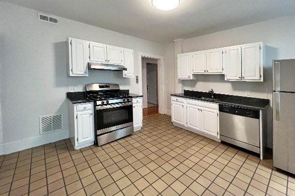 40 Calvin Street, Unit 2 Somerville, MA 02143 - Photo 5 of 12 a kitchen with granite countertop white cabinets and stainless steel appliances