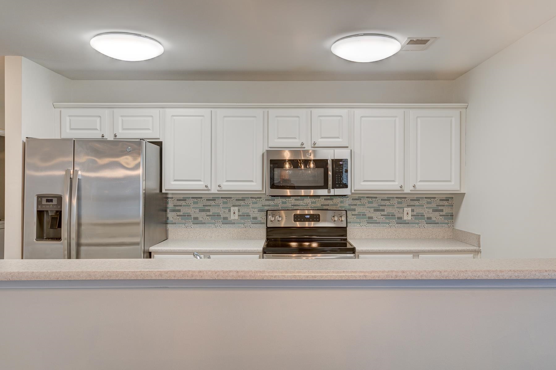 4826 Innisbrook Court, Unit 905 Myrtle Beach, SC 29579 - Photo 7 of 36 Kitchen with stainless steel appliances, tasteful backsplash, and white cabinetry