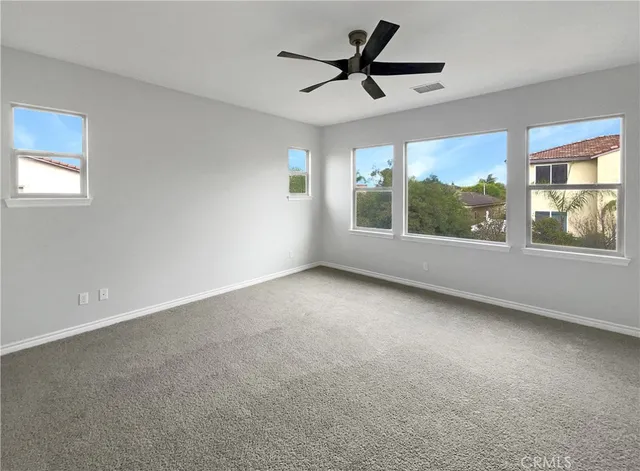 en empty room with windows and ceiling fan