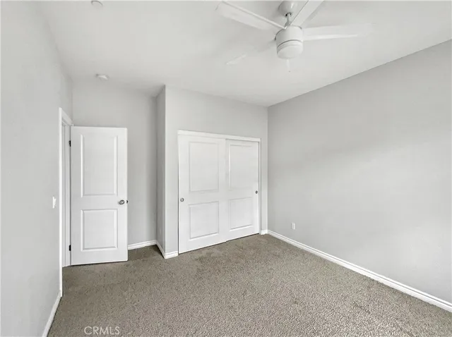 a view of an empty room and chandelier fan