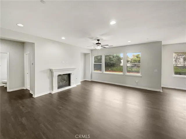 an empty room with wooden floor fireplace and windows