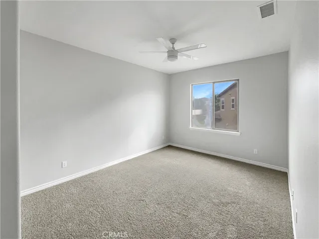 an empty room with windows and ceiling fan