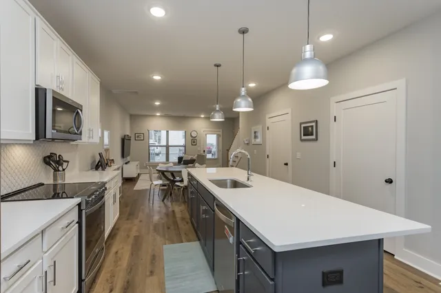 a kitchen with a stove a refrigerator a sink and chairs