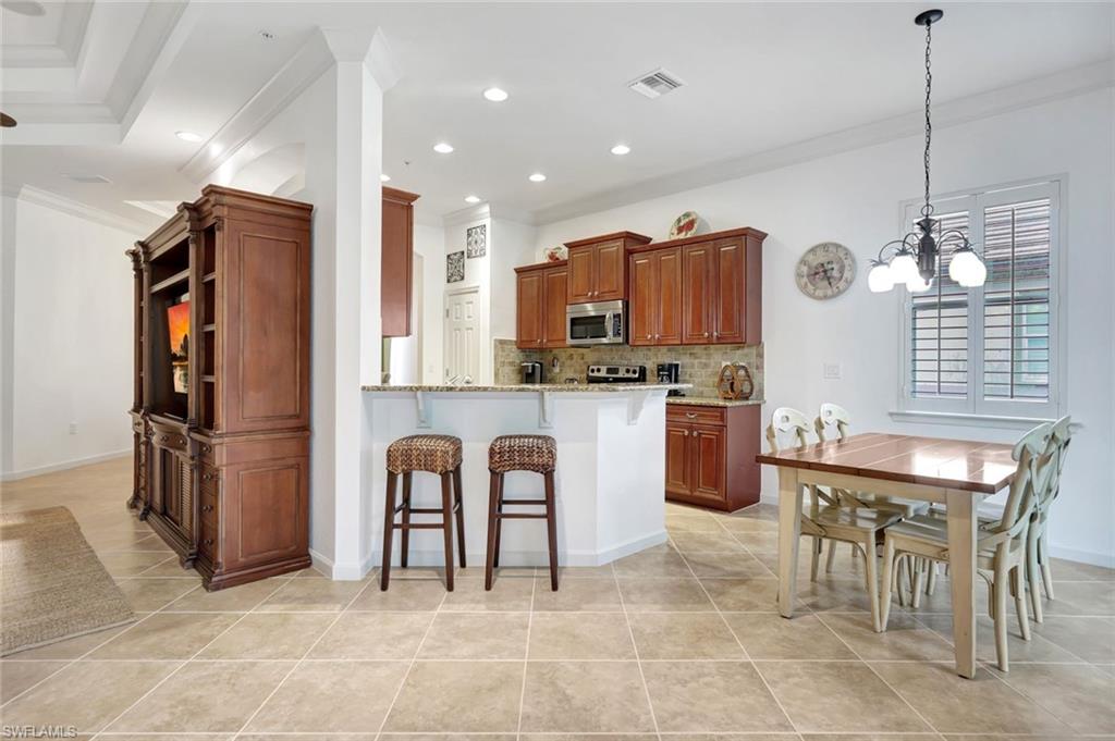 9508 Ironstone Terrace, Unit 201 Naples, FL 34120 - Photo 12 of 45 Kitchen featuring a kitchen bar, light stone countertops, recessed lighting, decorative backsplash, and a peninsula