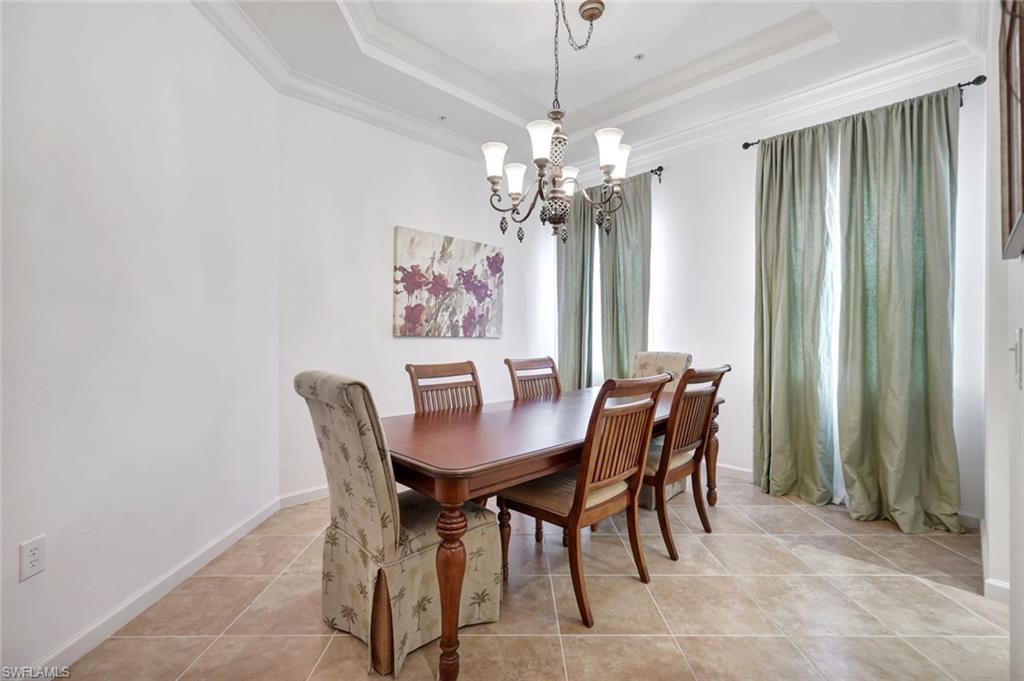9508 Ironstone Terrace, Unit 201 Naples, FL 34120 - Photo 15 of 45 Dining room featuring a chandelier, ornamental molding, a raised ceiling, and light tile patterned floors