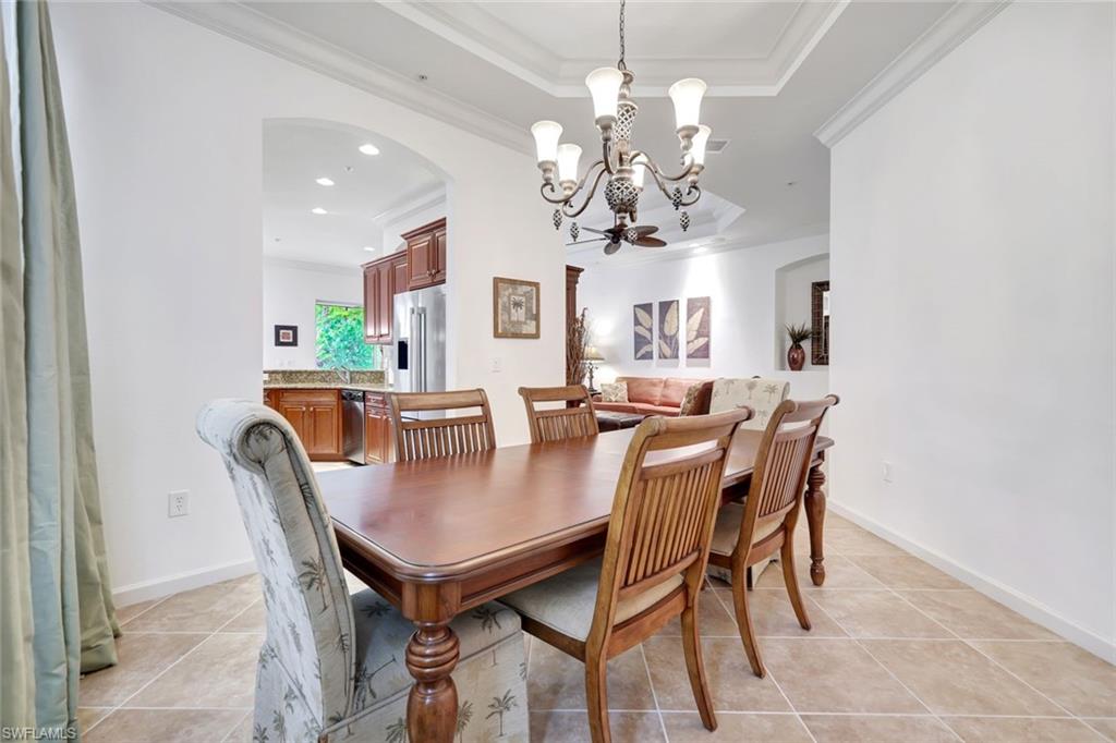9508 Ironstone Terrace, Unit 201 Naples, FL 34120 - Photo 16 of 45 Dining area with arched walkways, light tile patterned floors, ornamental molding, a chandelier, and a tray ceiling