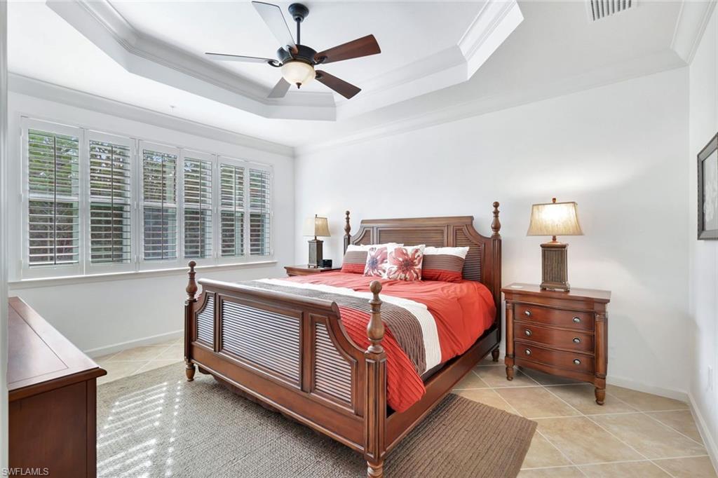 9508 Ironstone Terrace, Unit 201 Naples, FL 34120 - Photo 20 of 45 Bedroom with ornamental molding, light tile patterned flooring, ceiling fan, and a raised ceiling