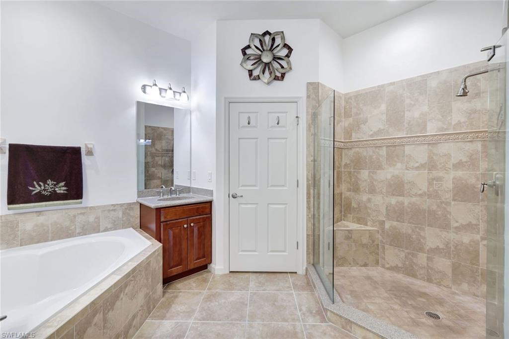 9508 Ironstone Terrace, Unit 201 Naples, FL 34120 - Photo 23 of 45 Full bathroom featuring a bath, light tile patterned floors, vanity, and a stall shower