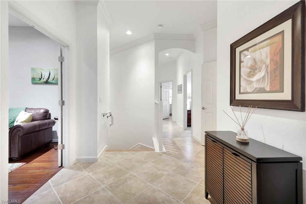 9508 Ironstone Terrace, Unit 201 Naples, FL 34120 - Photo 5 of 45 Hall with crown molding, light tile patterned flooring, arched walkways, and recessed lighting