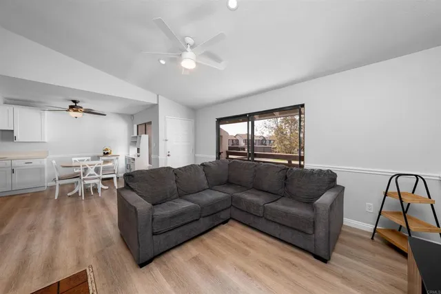 a living room with furniture and a dining table with wooden floor