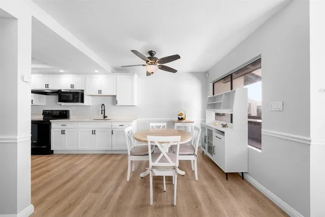 a kitchen with stainless steel appliances kitchen island granite countertop a refrigerator a stove a dining table and chairs with wooden floor