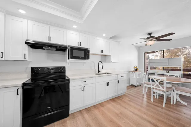 a kitchen with a stove a sink and wooden floor