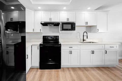 a kitchen with stainless steel appliances kitchen island granite countertop a refrigerator sink and white cabinets