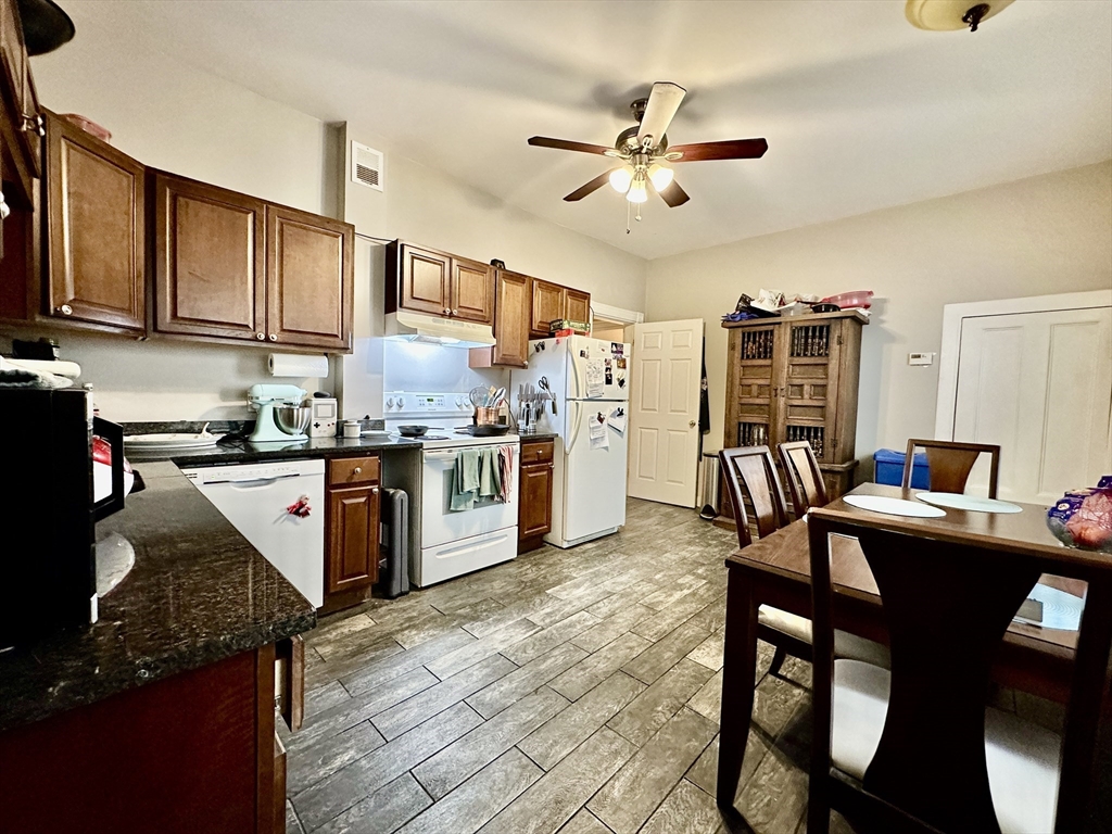 a kitchen with granite countertop kitchen island stainless steel appliances a table chairs sink and cabinets